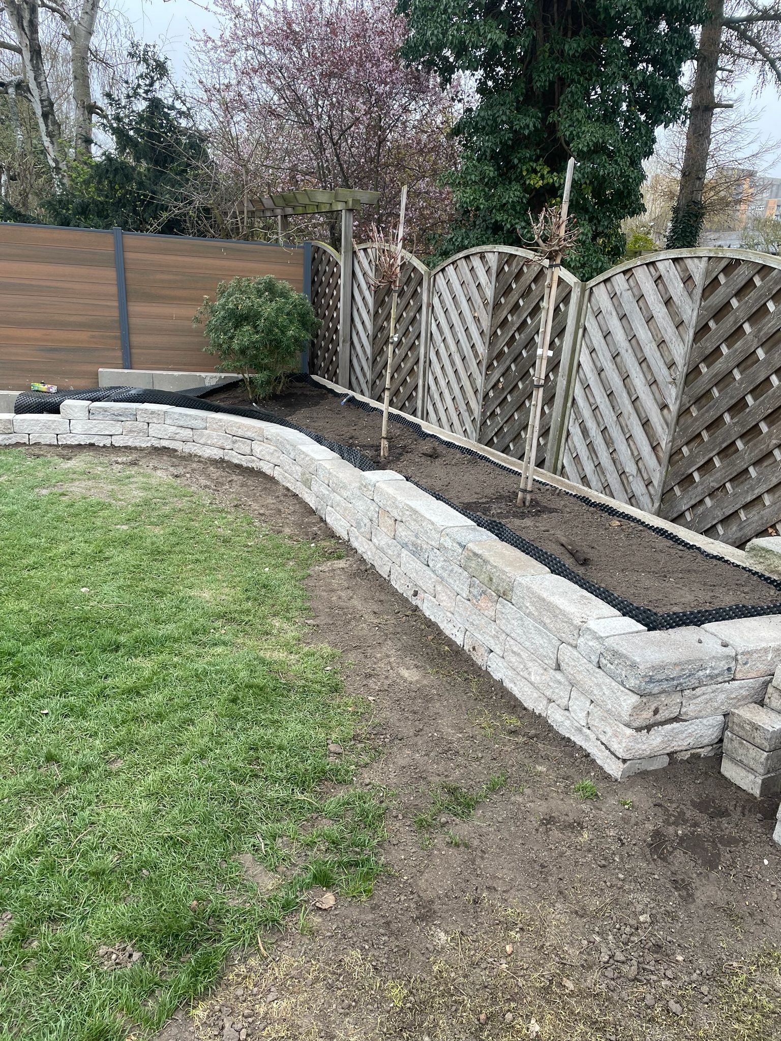 Natursteinmauer als Beeteinfassung mit frischer Bepflanzung und Sichtschutzelementen – Garten- und Landschaftsbau von TOJA Bau